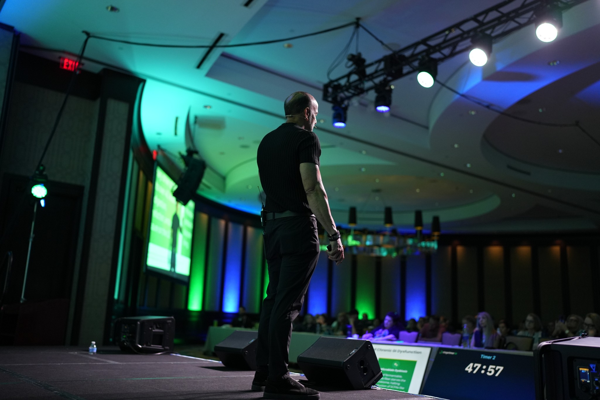 Speaker on stage under event lighting in a corporate conference ballroom